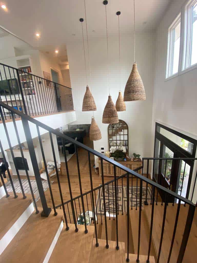 Elegant staircase design with black railings and wooden steps, illuminated by large windows and styl.